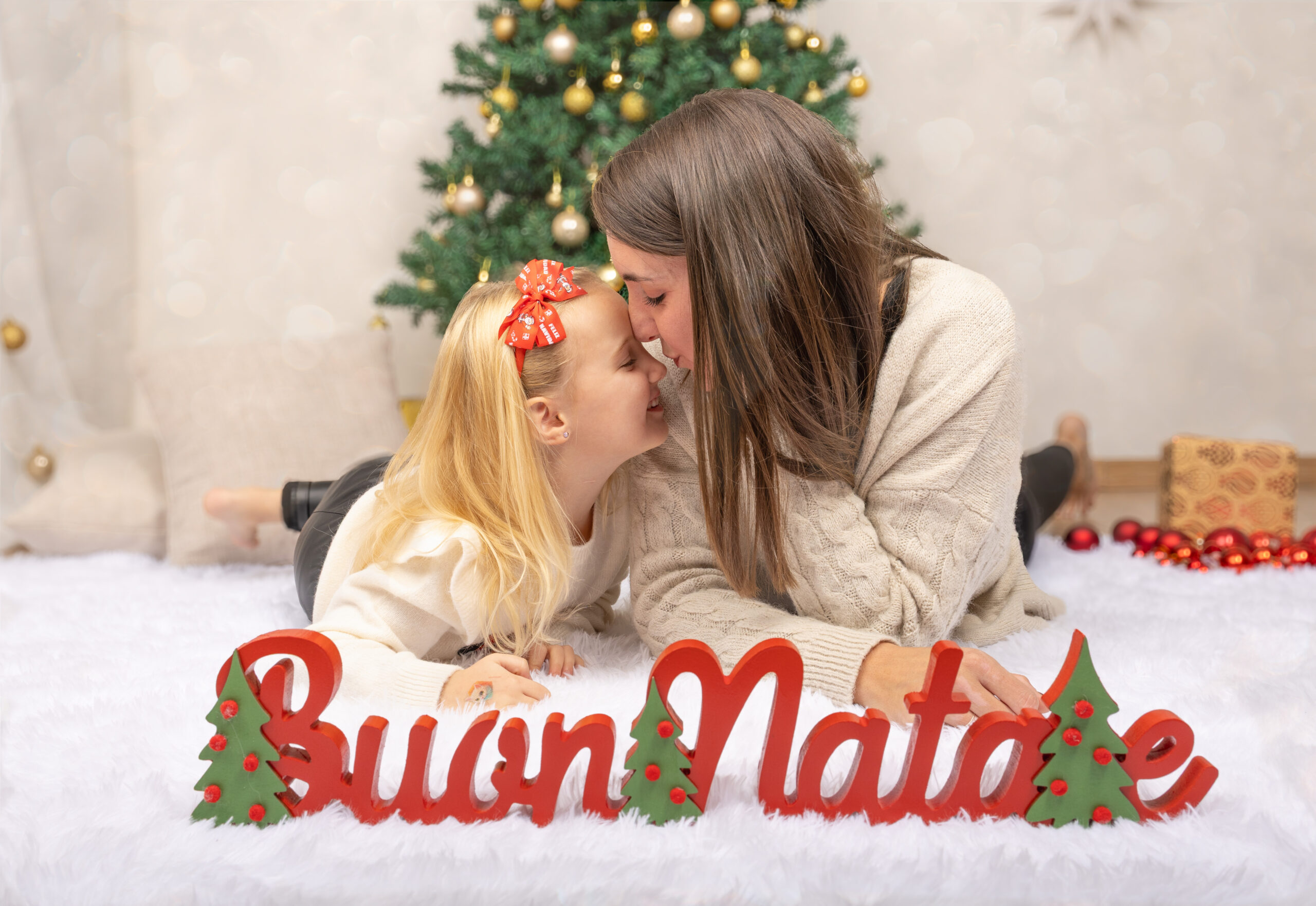Mamma e figlia guancia a guancia davanti all'albero di Natale