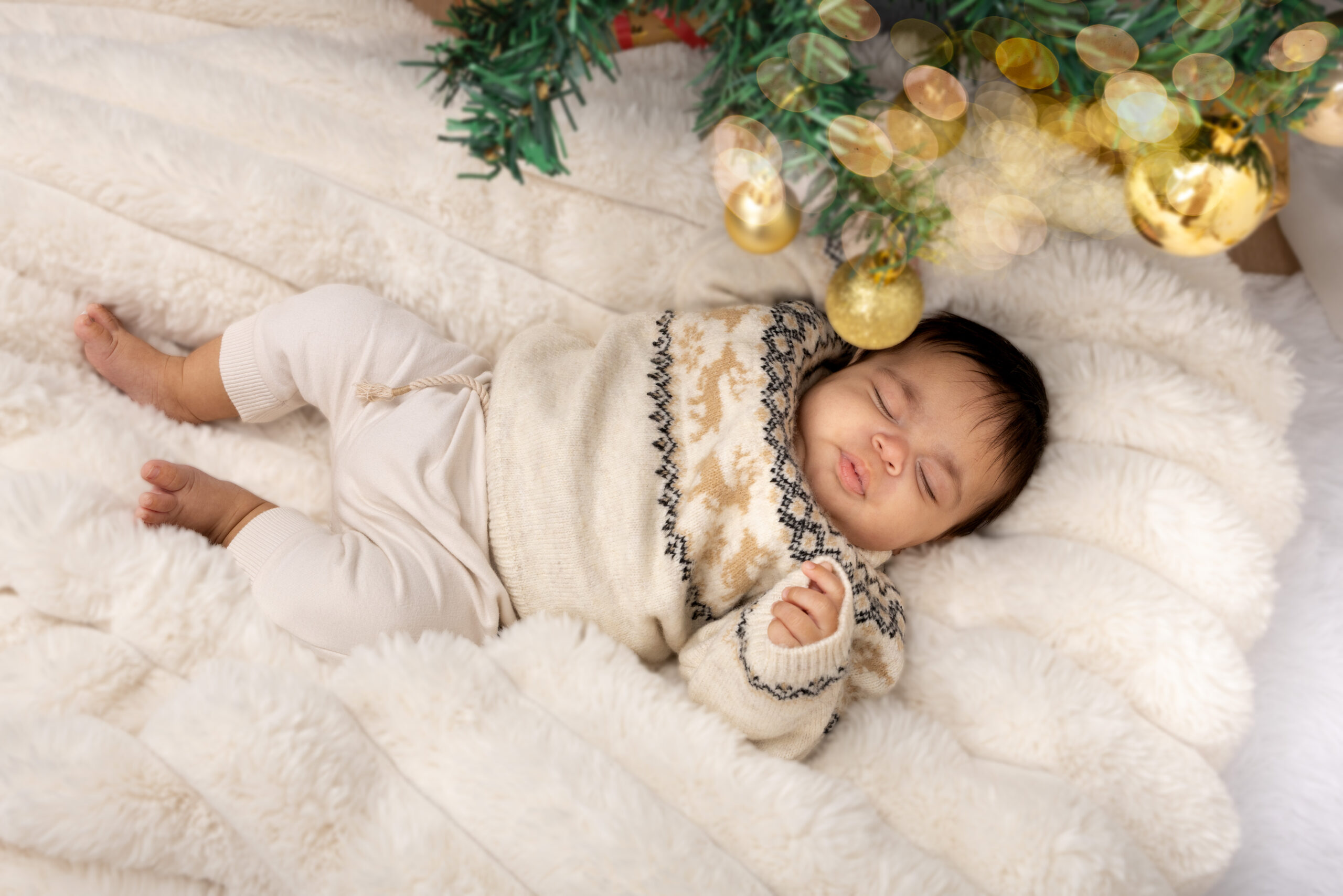 Neonato disteso su una coperta di pelo bianco accanto a un pupazzo di pan di zenzero durante una sessione fotografica di Natale
